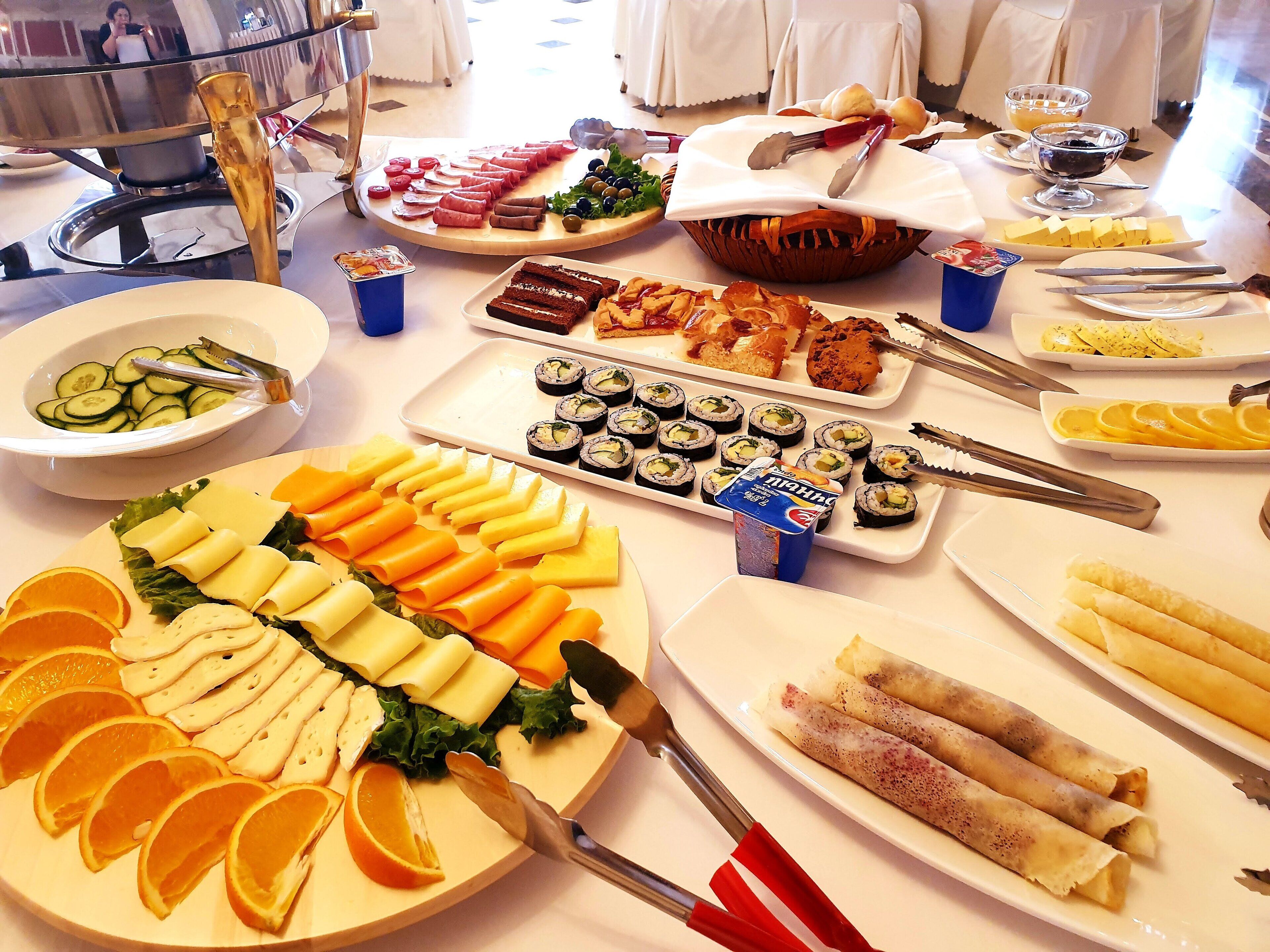 A buffet table with various food items including sushi, cheese, and pastries.