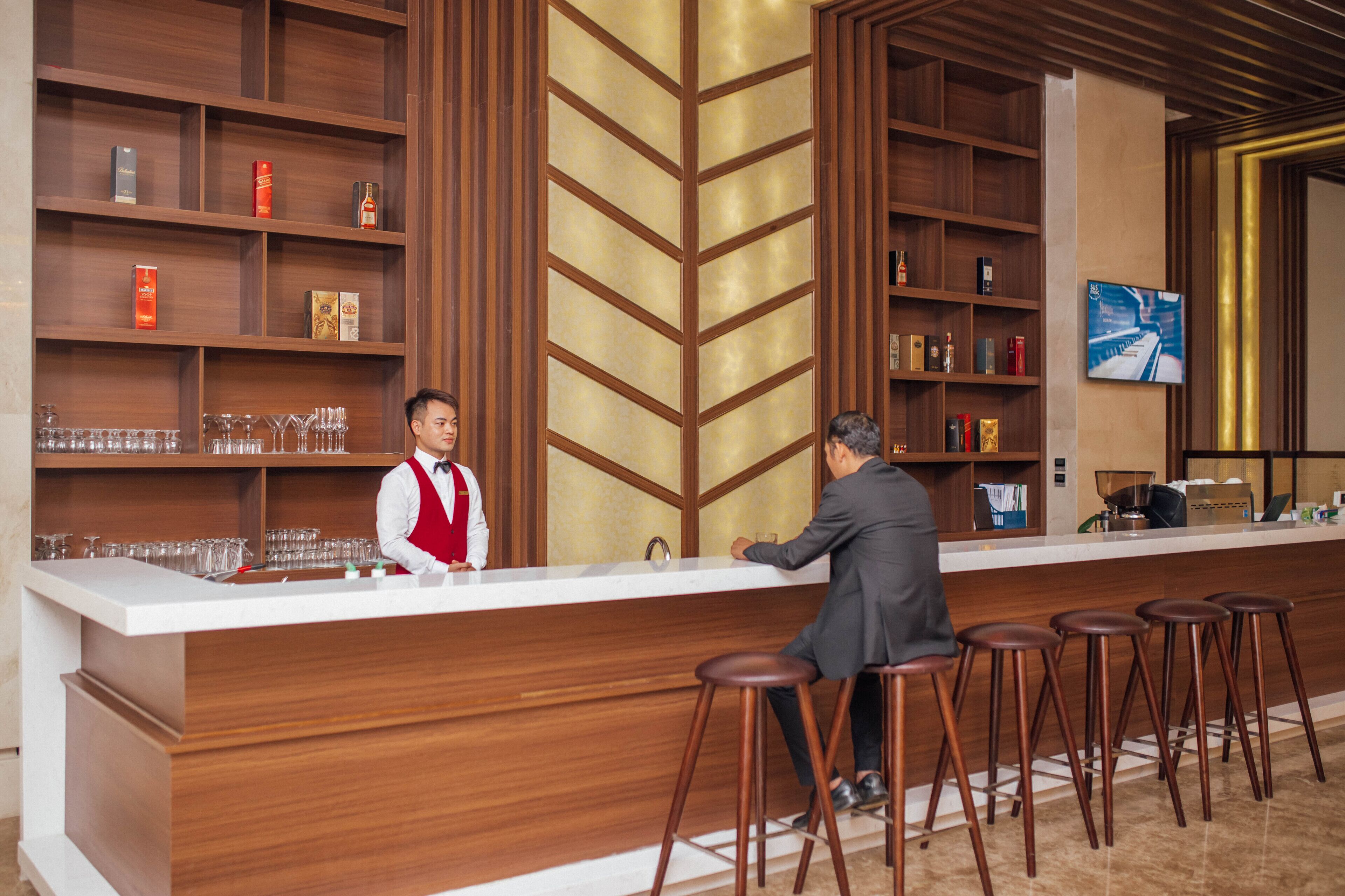 A bar area with wooden shelves, stools, and a counter.