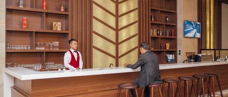 A bar area with wooden shelves, stools, and a counter.