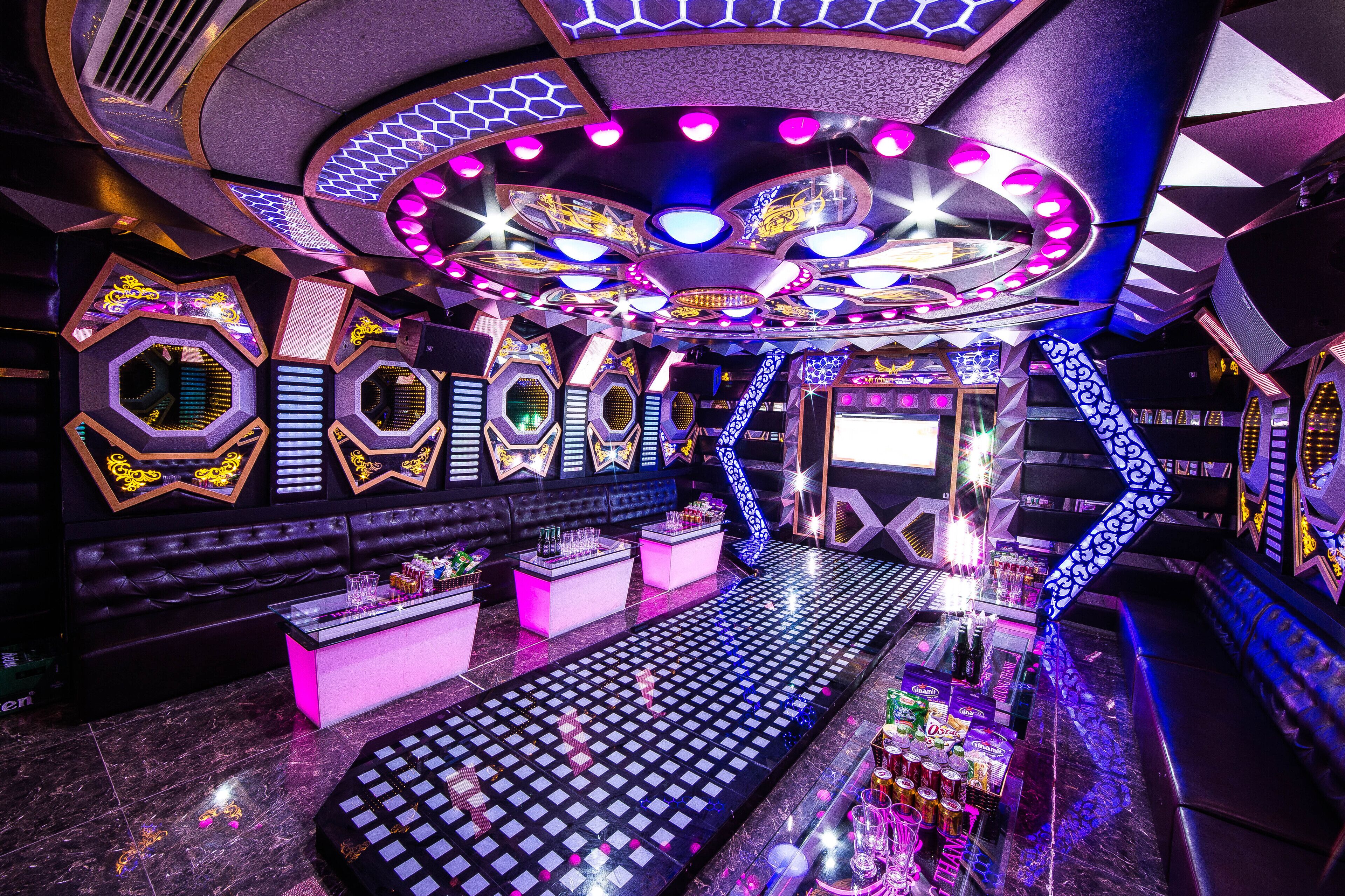 A bar area with a checkered floor, neon lights, and a bar counter with bottles.