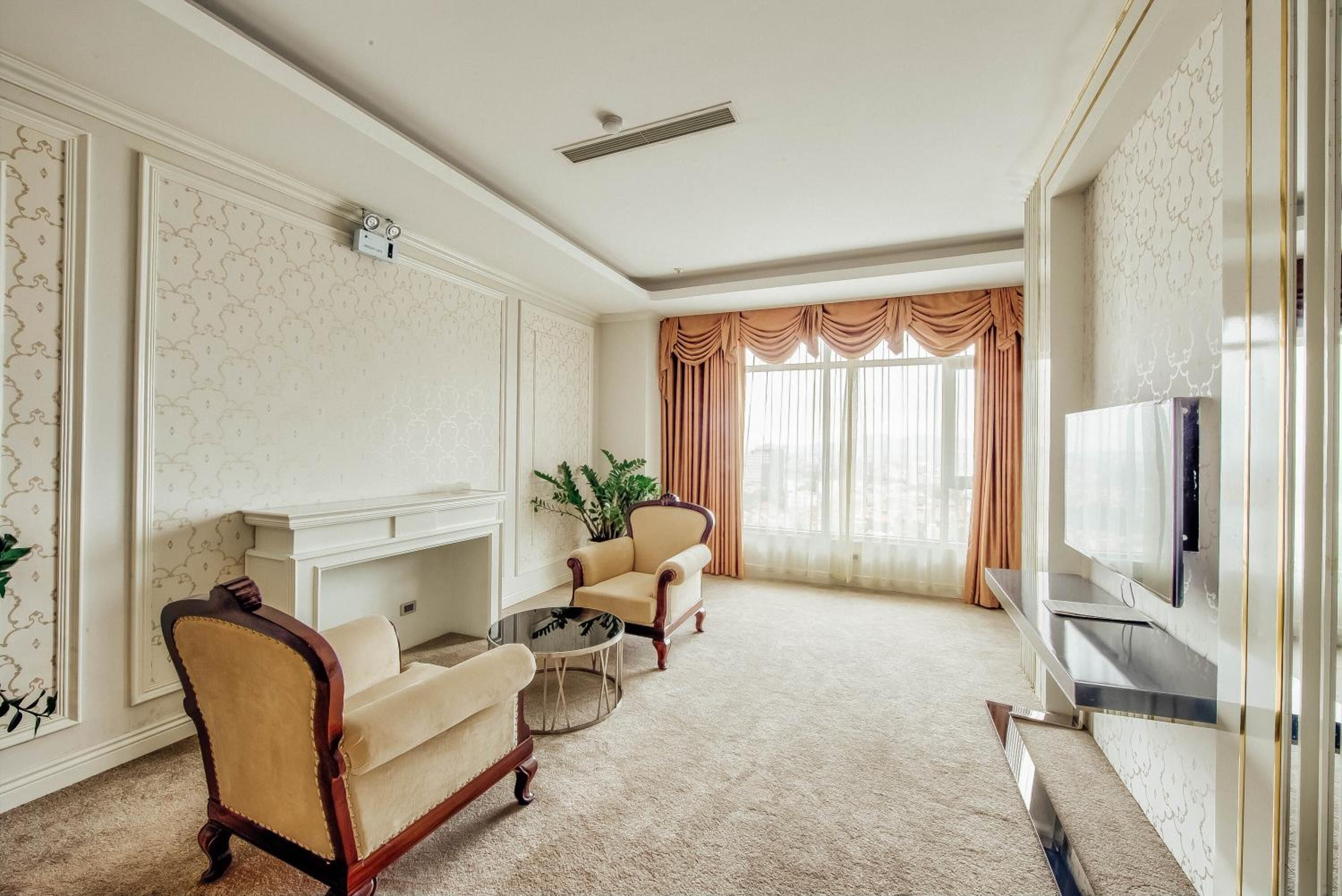 Amplia sala de estar con chimenea, dos sillones, una mesa de centro y un televisor.