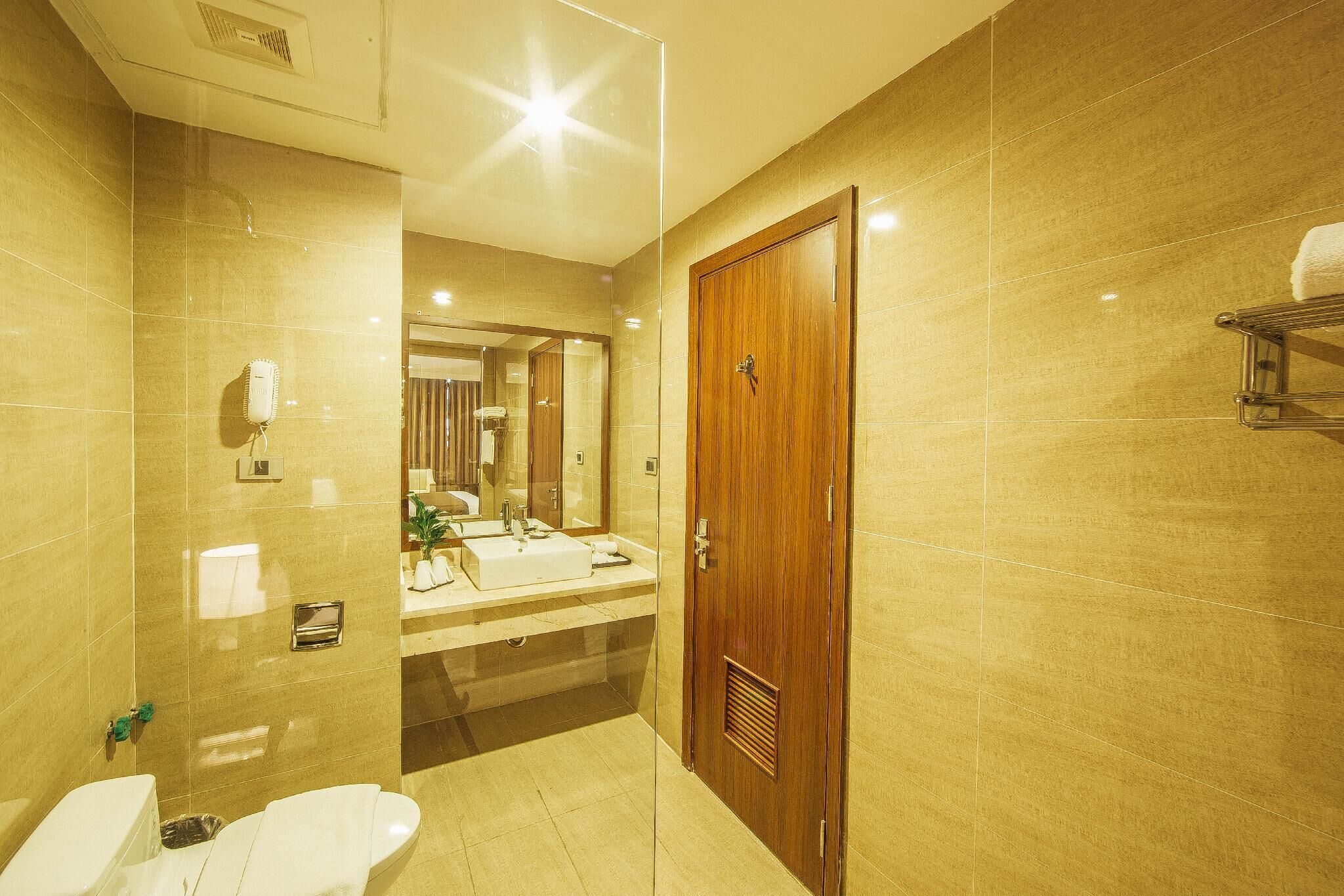 A modern bathroom with a large mirror, a sink, and a toilet.
