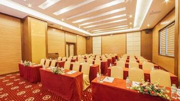 A conference room with rows of tables, each with a red tablecloth and floral centerpieces.