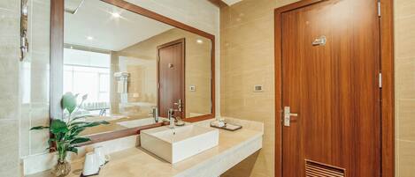 Un baño moderno con un espejo grande, un lavamanos blanco y una puerta de madera.