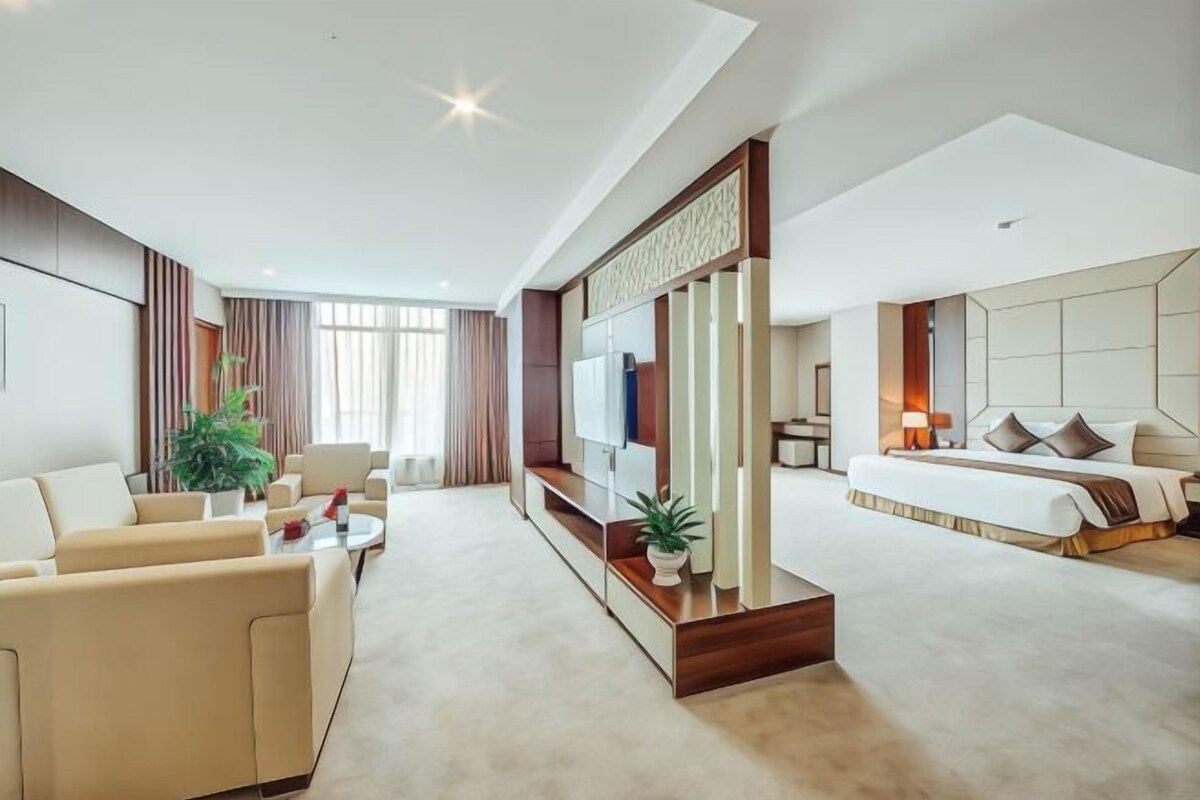 Una habitación de hotel moderna con sala de estar, cama grande y televisión.