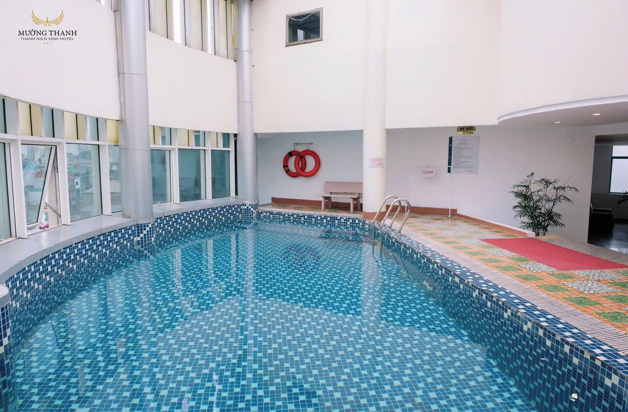 An indoor swimming pool with tiled walls and a clear view of the cityscape through large windows.
