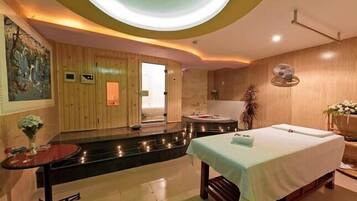 Relax in a serene spa room with a massage table, wall-mounted chair, and a small table with a vase of flowers.