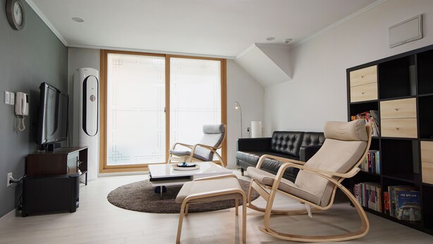 A modern living room with a sofa, a rocking chair, a coffee table, and a bookshelf. - Until Stephen Chow Comes - Hostel (Seoul)