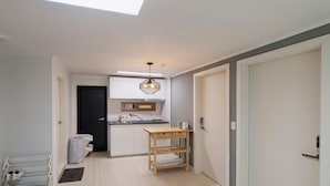 A modern kitchen with a skylight, a wooden table, and a built-in oven. - Until Stephen Chow Comes - Hostel (Seoul)