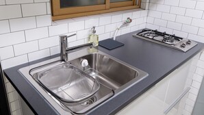 A kitchen with a stainless steel sink, a gas stove, and a window above the sink. - Until Stephen Chow Comes - Hostel (Seoul)