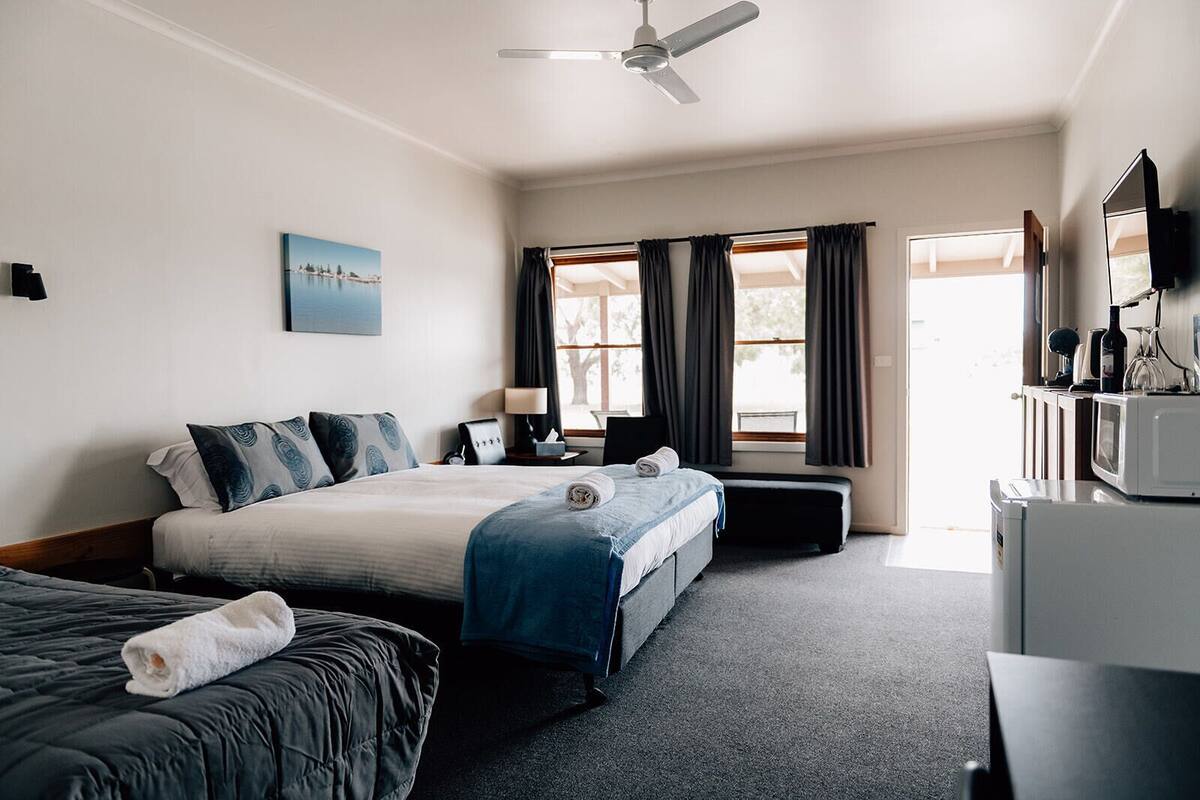 A hotel room with a bed, a desk, a chair, a television, and a window with curtains.