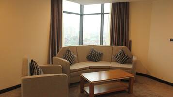 A living room with a sofa set, a coffee table, and a large window with curtains.