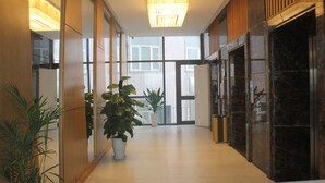 A modern hotel lobby with a long corridor, large windows, and potted plants. - Muong Thanh Cua Dong Hotel (Truong Vinh)