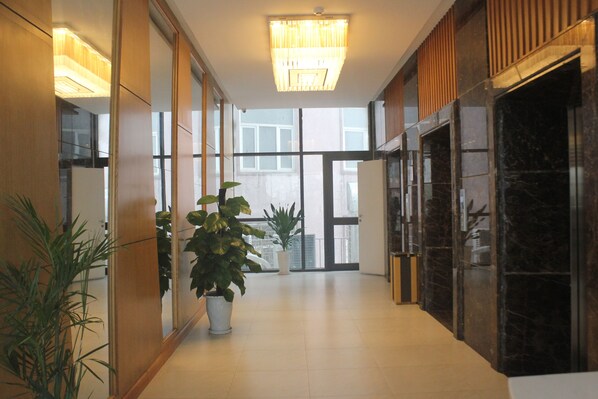 A modern hotel lobby with a long corridor, large windows, and potted plants. - Muong Thanh Cua Dong Hotel (Truong Vinh)