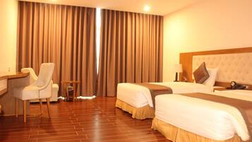 A hotel room with two beds, a desk, a chair, and a small table.