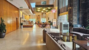 A hotel lobby with a reception desk, seating area, and a large plant. - Muong Thanh Cua Dong Hotel (Truong Vinh)
