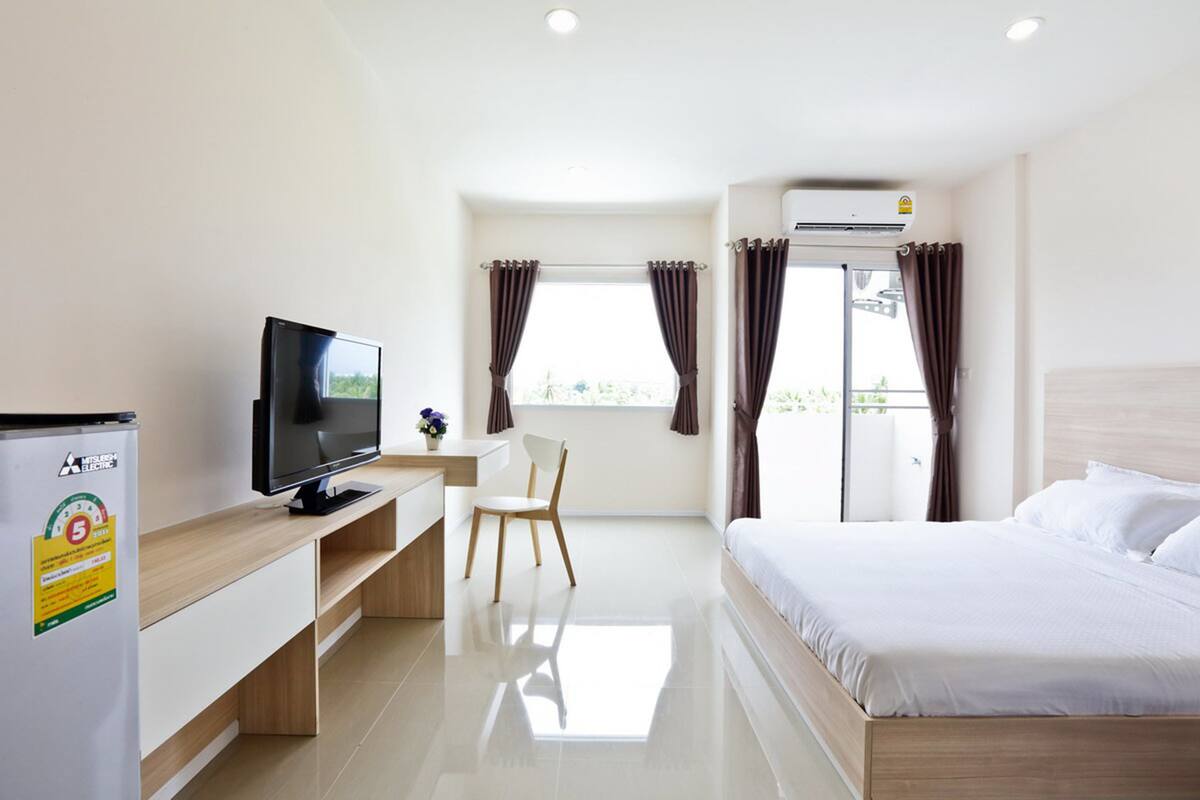 A hotel room with a bed, a TV, a desk, and a chair.