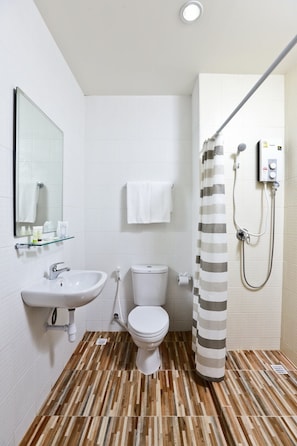 Un baño con piso de madera, baldosas blancas, un lavamanos, un inodoro y una ducha con cortina a rayas.