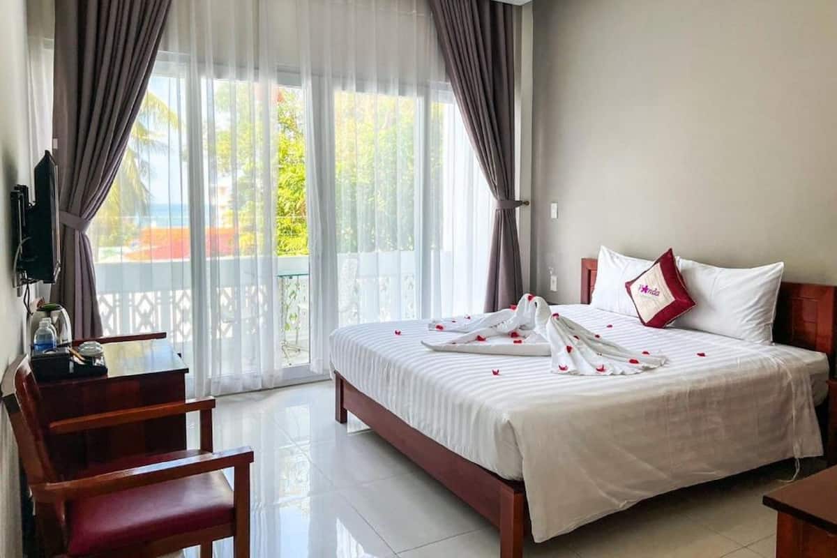 A hotel room with a bed, a desk, and a chair.