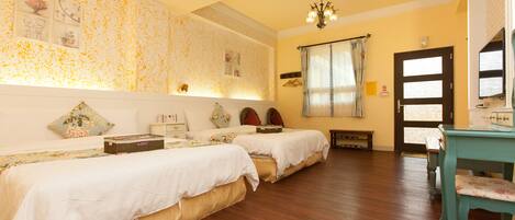 A room with two beds, a wooden floor, a desk with a chair, and a door.