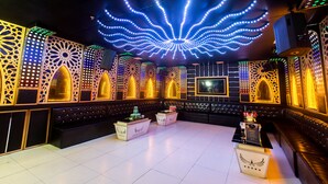 A room with a white floor, black leather seating, and decorative light patterns on the walls.