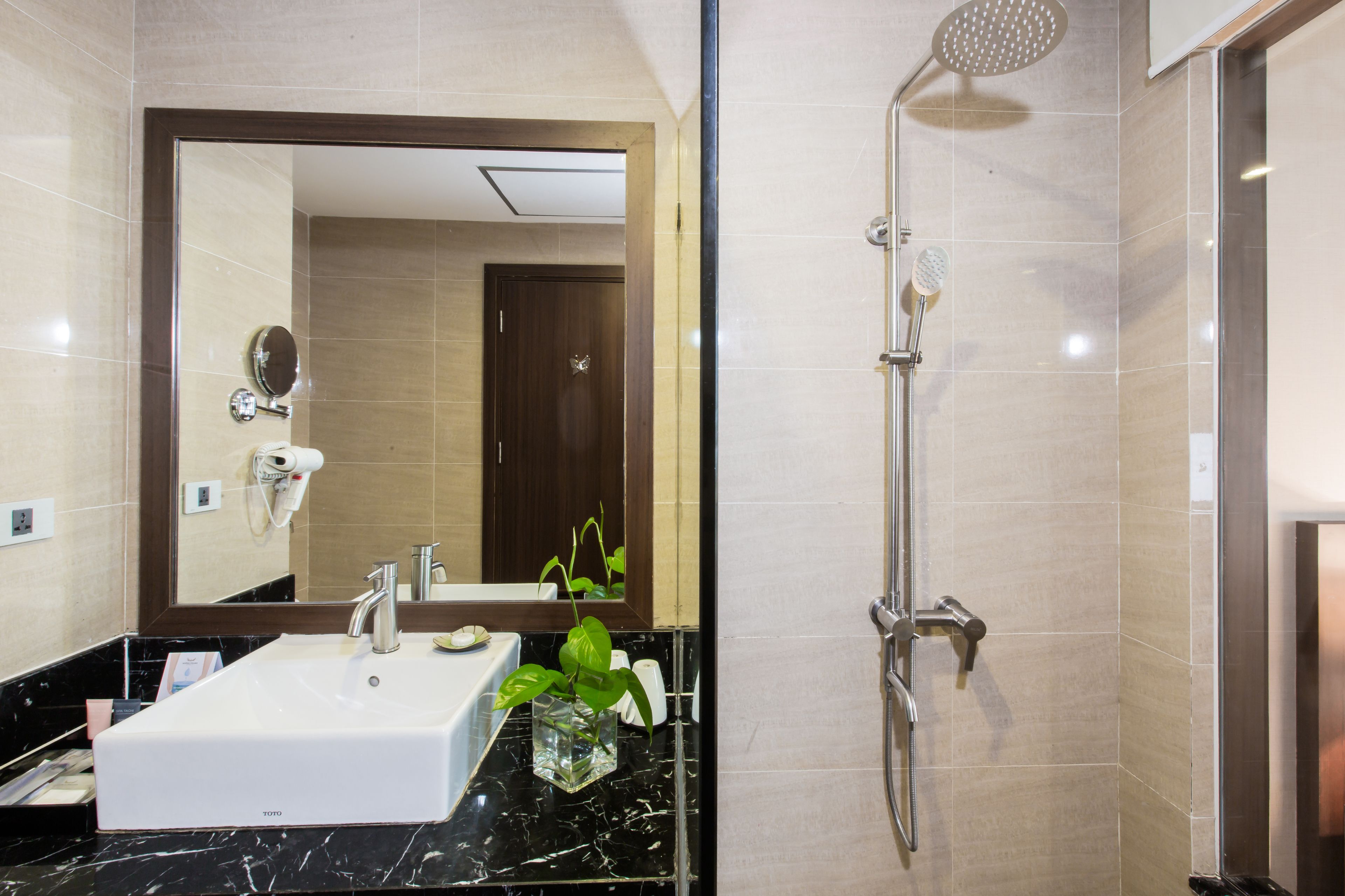 A modern bathroom with a white sink, a large mirror, and a shower with a handheld showerhead.