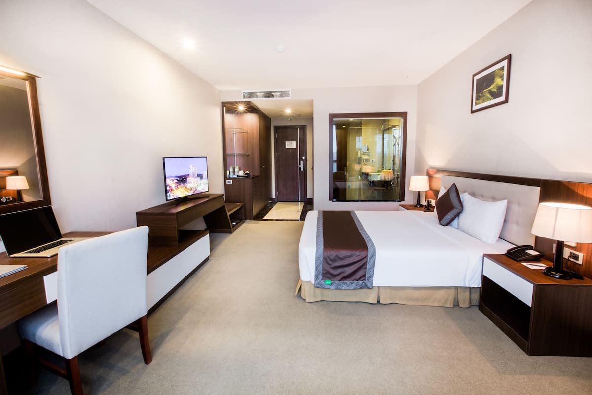 A hotel room with a bed, desk, chair, TV, and a bathroom visible through an open door.