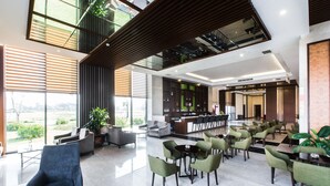 A spacious lobby with a reception desk, seating areas, and large windows offering views of the outdoors.