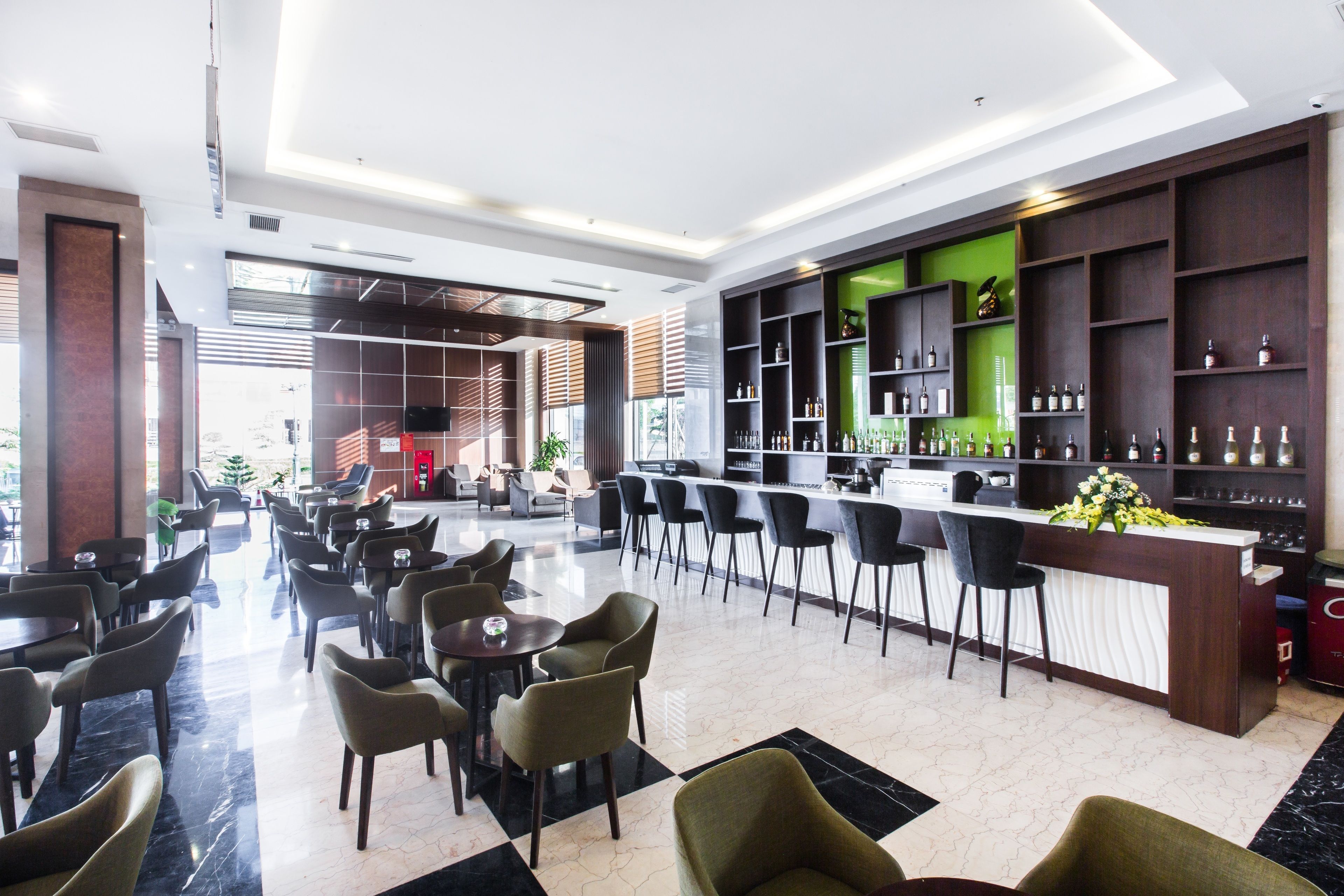 A modern bar area with a counter, seating, and shelves with bottles.