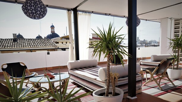 A rooftop terrace with a sofa, chairs, a table, and potted plants. - MD Design Hotel Portal del Real (Valencia)