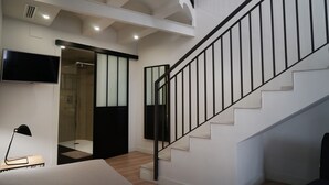A modern interior with a staircase, a flat-screen TV, and a shower area. - MD Design Hotel Portal del Real (Valencia)