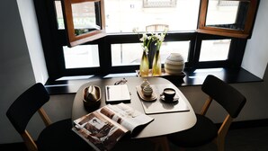 A table with a magazine, a cup of coffee, and a vase with flowers by a window. - MD Design Hotel Portal del Real (Valencia)