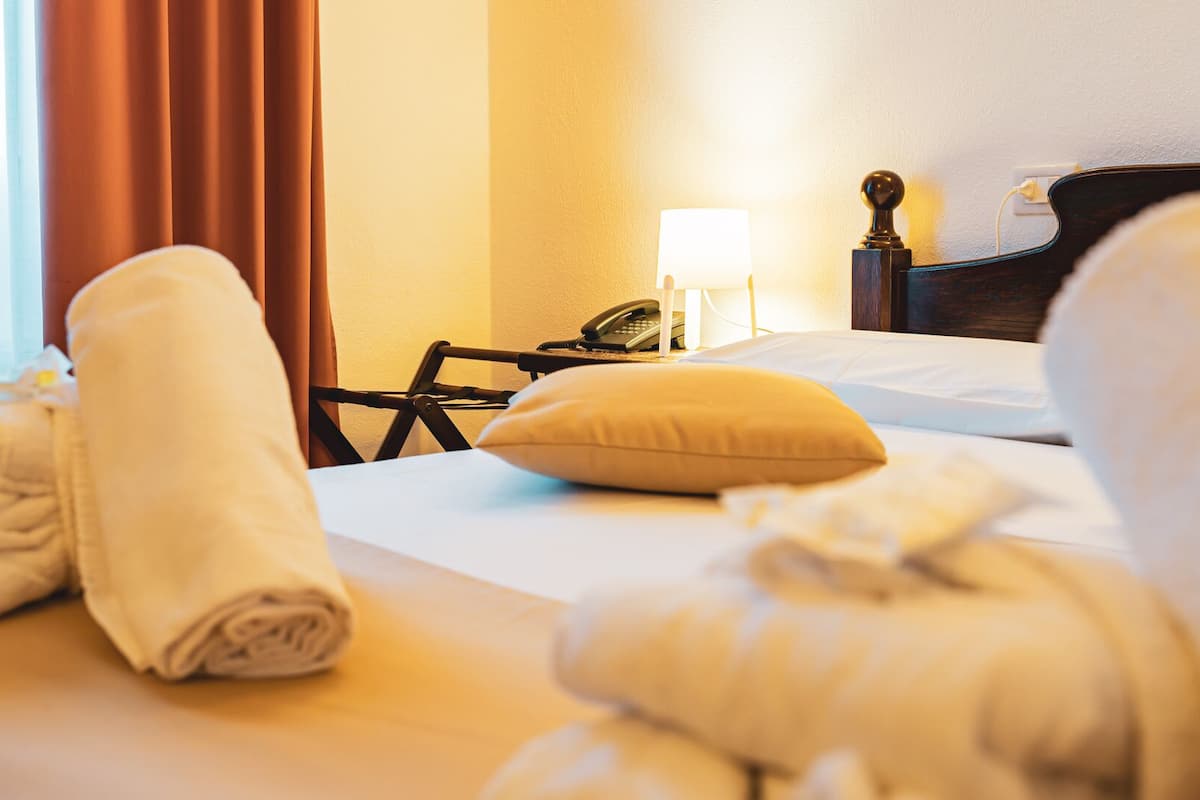 Ein Hotelzimmer mit Bett, Sessel, Lampe und Telefon.