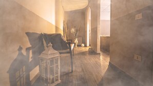 Un couloir avec un plancher en bois, une chaise, une lanterne et un vase contenant des plantes séchées.