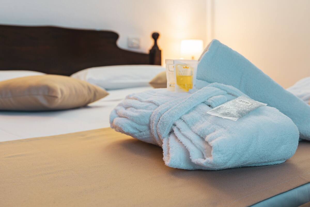 Ein ordentlich bezogenes Bett mit einem blauen Handtuch und einem Glas Wasser auf dem Nachttisch.