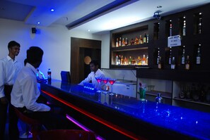 Eine Bar mit einem Barkeeper, Regalen voller Spirituosenflaschen und einer neongetränkten Theke.