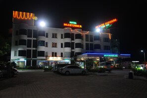 A multi-story hotel with a prominent neon sign for 'Hotel Milestone Z' and 'Sakthi Saravana Pure Veg'.