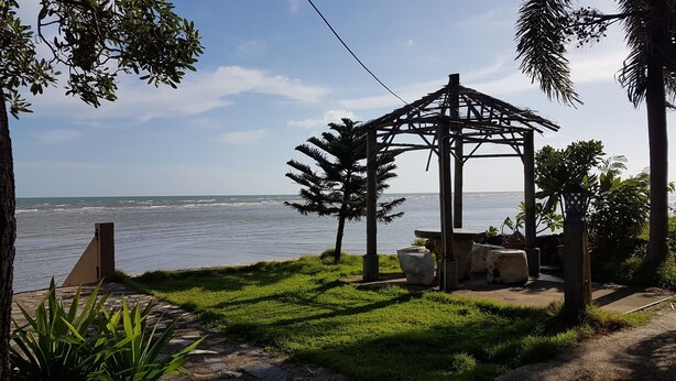Un quiosco con vistas al mar, rodeado de vegetación y un sendero de piedra.
