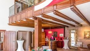 A spacious lobby with a wooden staircase, a reception desk, and a seating area. - Hotel Vorderburg (Schlitz)