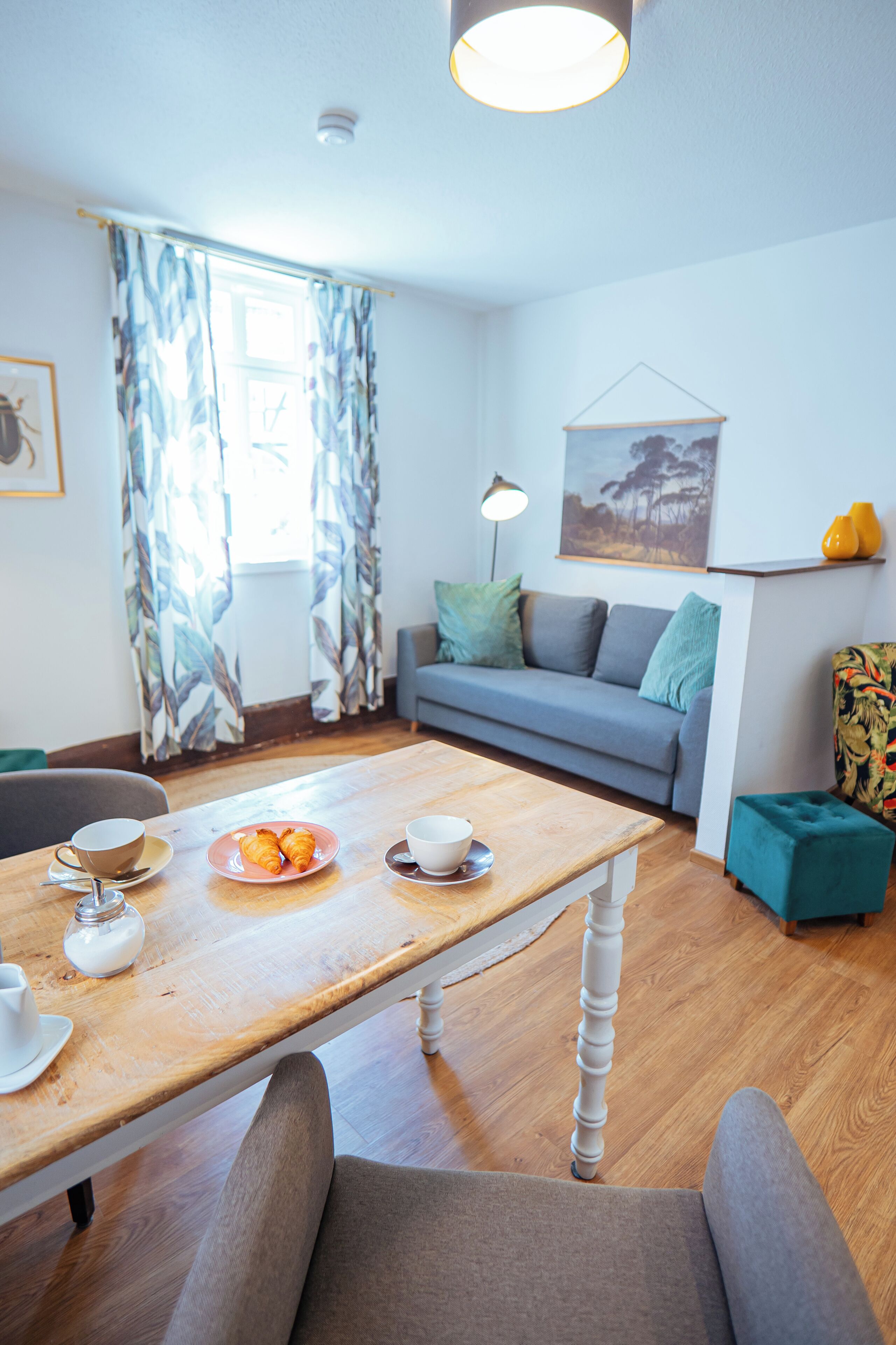 Una sala de estar moderna con una mesa de comedor de madera, un sofá gris y un cuadro en la pared.