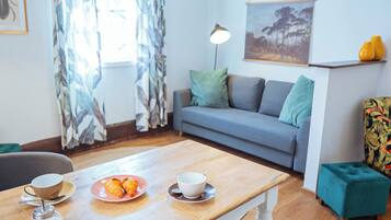 Una sala de estar moderna con una mesa de comedor de madera, un sofá gris y un cuadro en la pared.