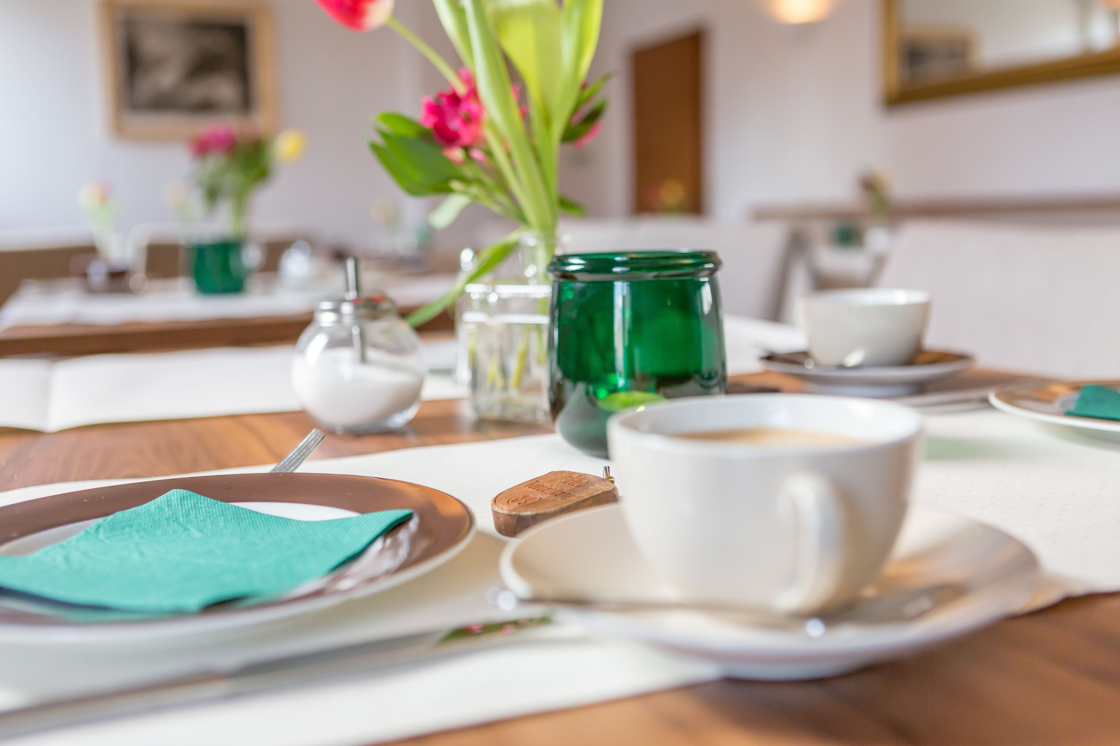 Un tavolo apparecchiato con piatti, tazze e un barattolo di vetro verde.