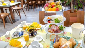 Een ontbijtsetting met borden eten, een schotel fruit en een mand met brood.