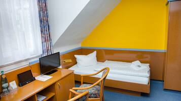 Habitación de hotel con cama, escritorio, silla y televisión.