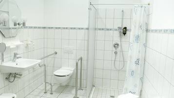 A bathroom with a white sink, toilet, and shower area.