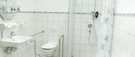 Un baño con lavamanos, inodoro y zona de ducha blanca.