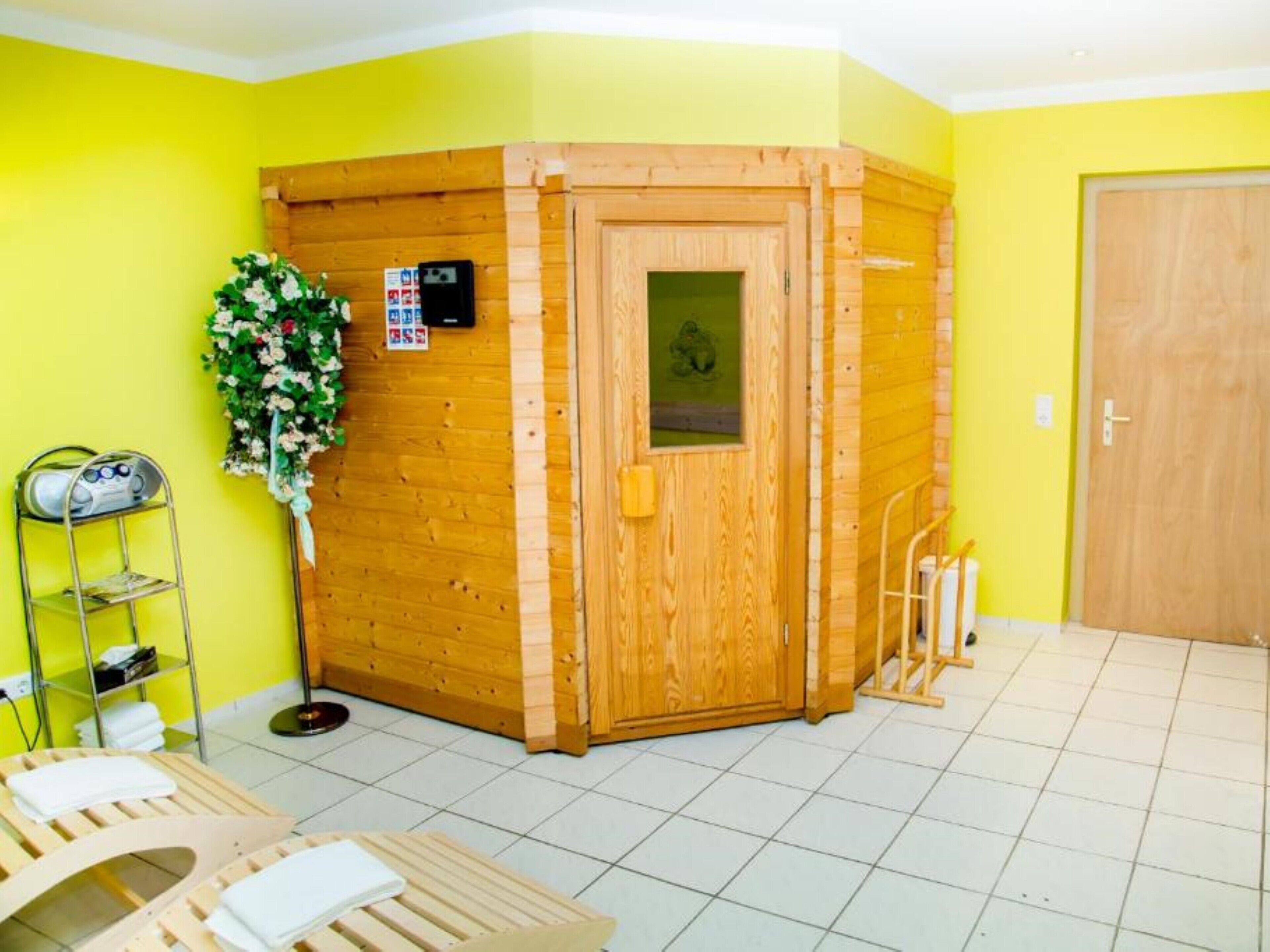Un sauna avec des murs en bois, une porte et une petite fenêtre. On y trouve un porte-serviettes et une étagère avec des serviettes.