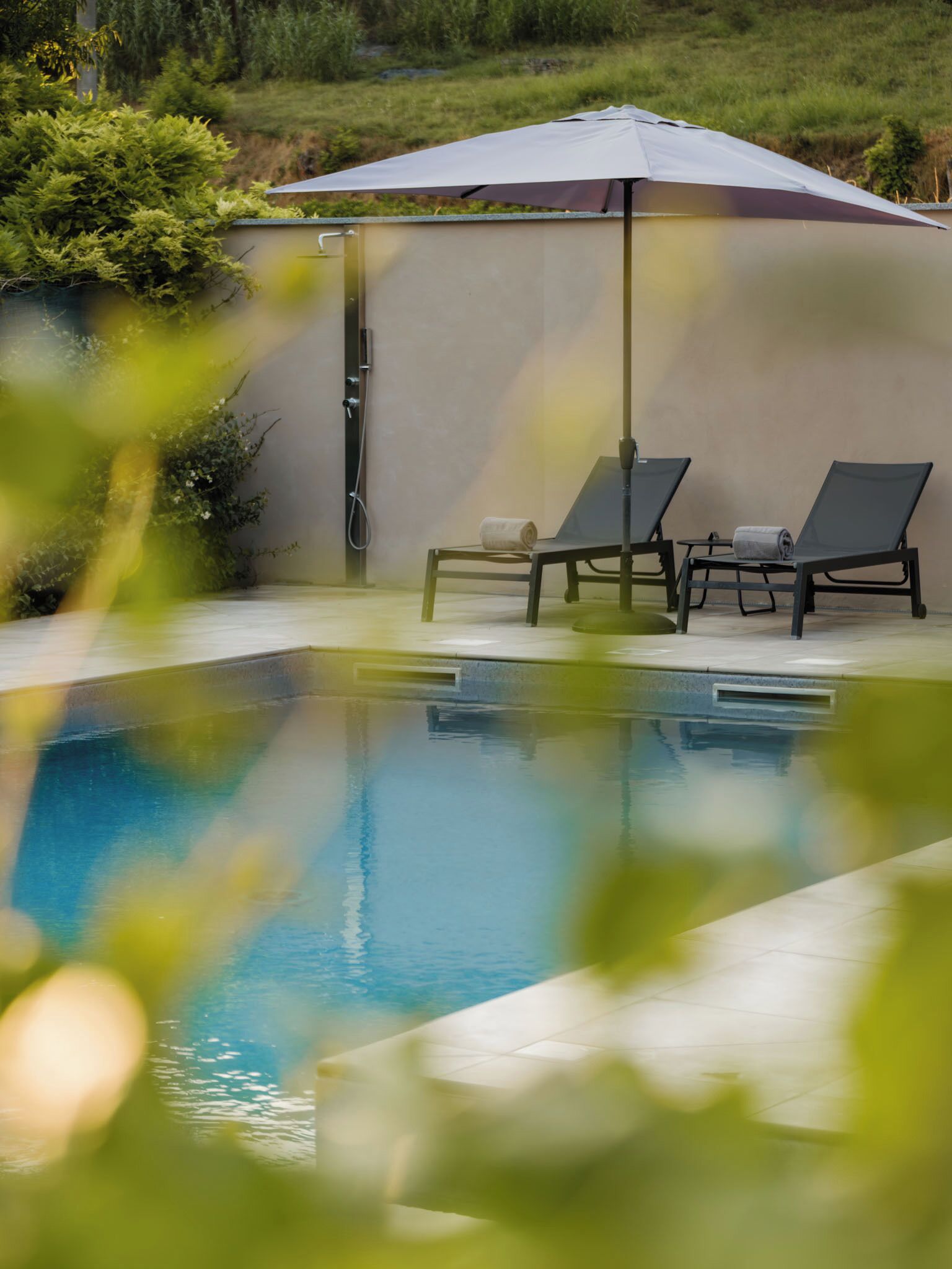 Une piscine avec deux chaises longues et un espace abrité.
