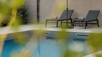 Une piscine avec deux chaises longues et un espace abrité.