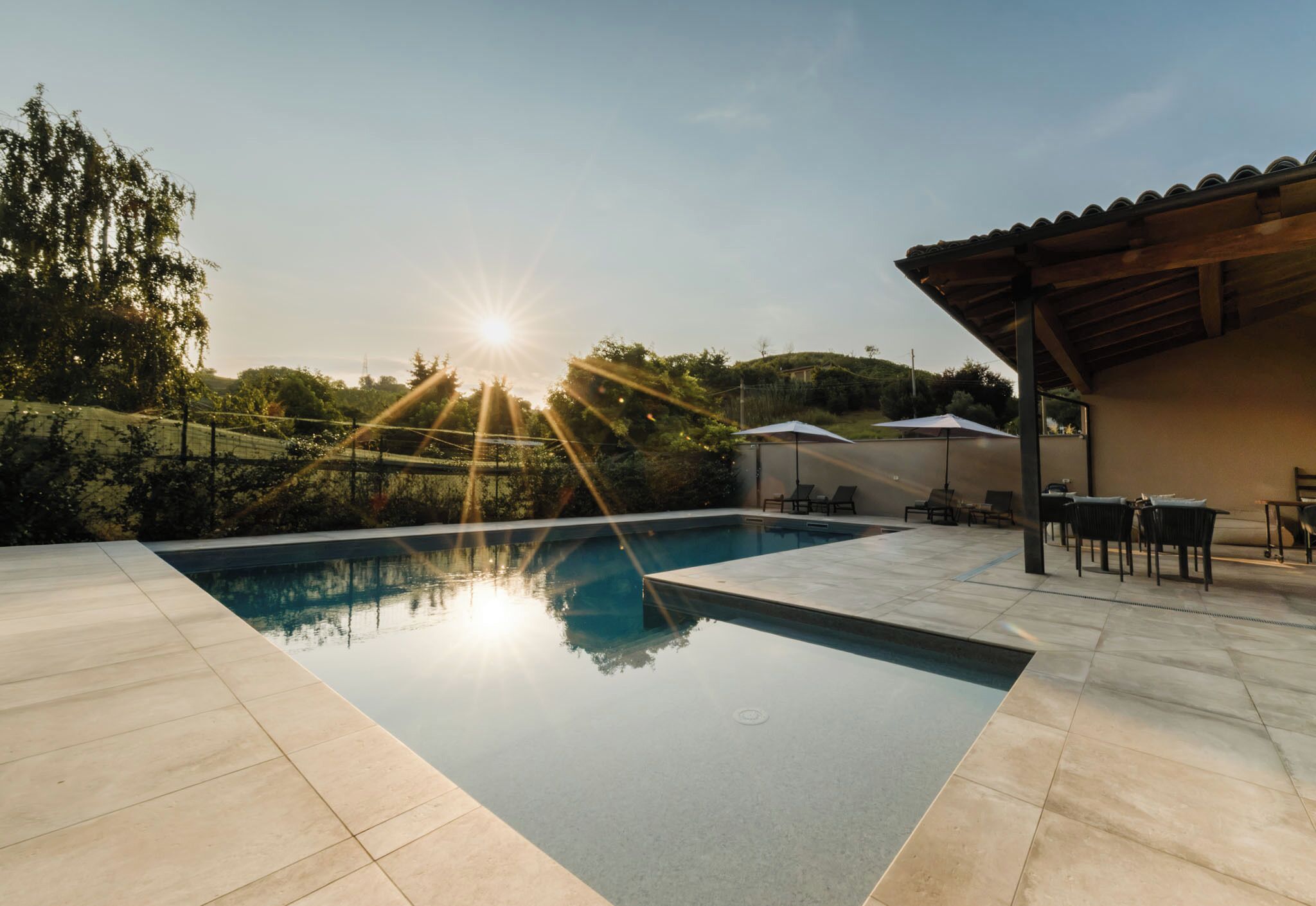 A swimming pool with a clear view of the sky and surrounding greenery.